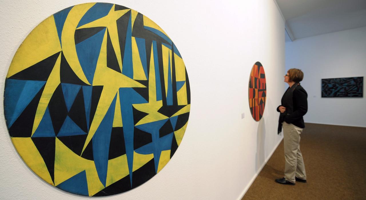 Eine Frau betrachtet in einem Austellungsraum kreisrunde Bilder, gefüllt mit geometrischen Formen in kräftigen Farben: Ausstellung der Künstlerin Carmen Herrera in der Pfalzgalerie in Kaiserslautern.
