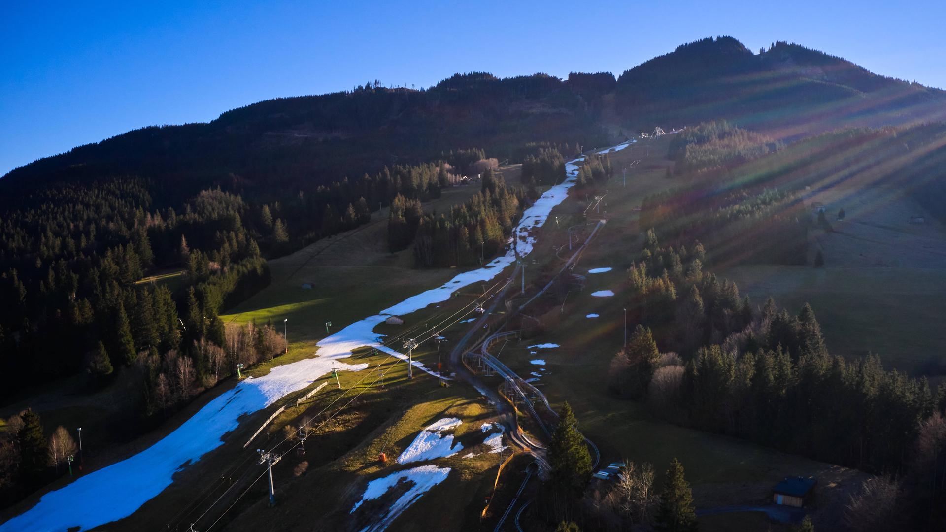 Blick von oben auf ein Alpenpanorama mit weißen Pisten-Streifen mit Kunstschnee umrahmt von grünen Wiesen wie in Nesselwang Blick von oben auf ein Alpenpanorama mit weißen Pisten-Streifen mit Kunstschnee umrahmt von grünen Wiesen wie in Nesselwang