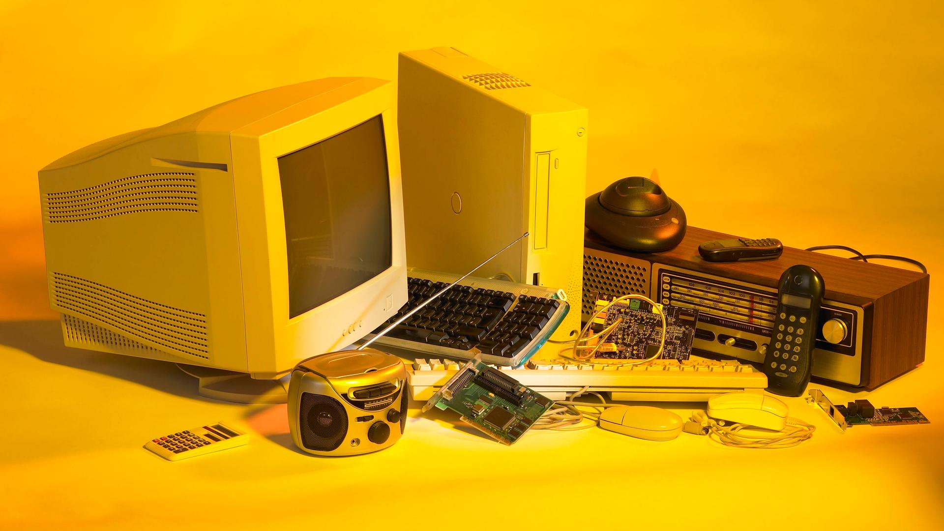 Elektroschrott wie ein alter PC und alte Handys vor gelben Hintergrund. Elektroschrott wie ein alter PC und alte Handys vor gelben Hintergrund.