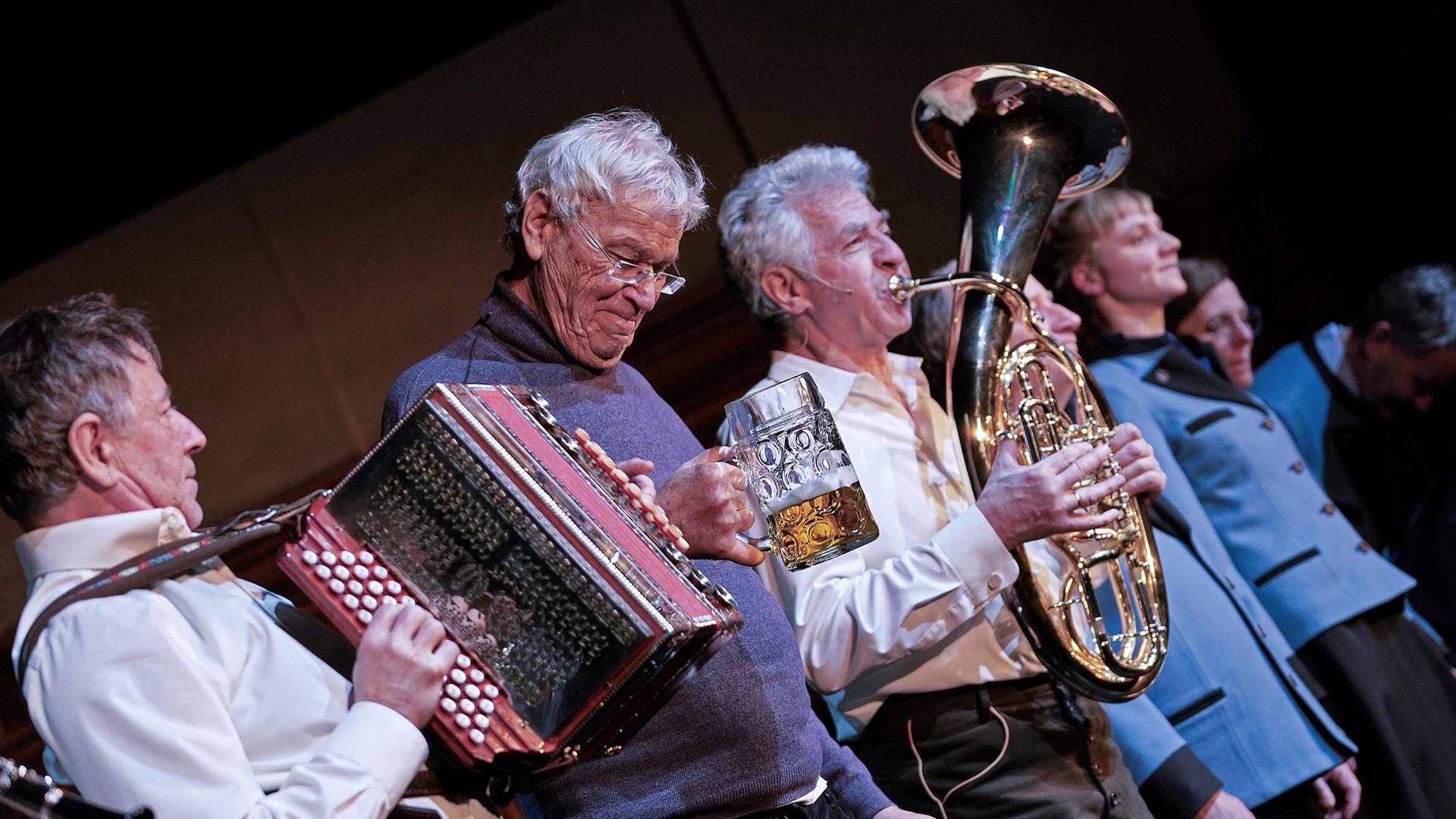 Gerhard Polt und die Well-Brüder musizierend auf der Bühne. Gerhard Polt und die Well-Brüder musizierend auf der Bühne.