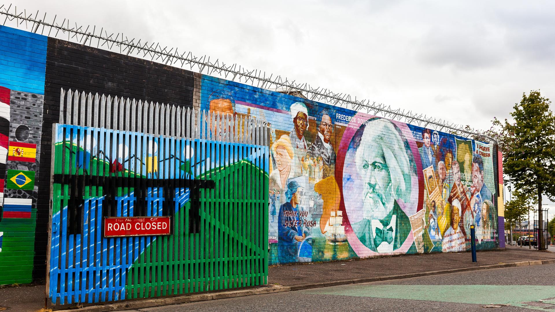 Wandbemalungen in der Northumberland Street, nahe der Falls Road in Belfast. Davor ein Tor mit der Aufschrift "Road closed", das eine sogenannte Peace Line (Friedenslinie) zur Trennung von Konfliktparteien darstellt. Abends wird das Tor geschlossen. Wandbemalungen in der Northumberland Street, nahe der Falls Road in Belfast. Davor ein Tor mit der Aufschrift "Road closed", das eine sogenannte Peace Line (Friedenslinie) zur Trennung von Konfliktparteien darstellt. Abends wird das Tor geschlossen.