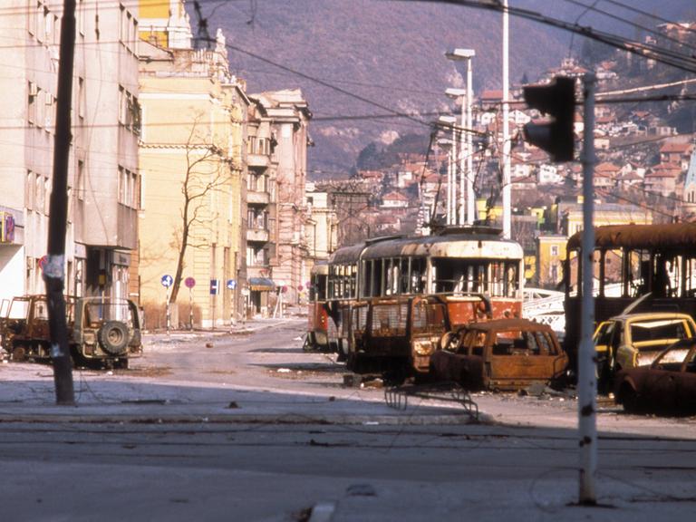Straße mit zerstörten Straßenbahnwaggons und Autos in Sarajevo 1993.