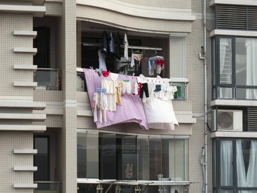 Bunte Wäsche hängt von einem Balkon eines Hochhauses.
