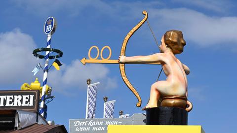 Wegweiser zu den Toiletten vom Oktoberfest 2022 auf der Theresienwiese zeigt einen Jungen auf einem Töpfchen mit Pfeil und Bogen.