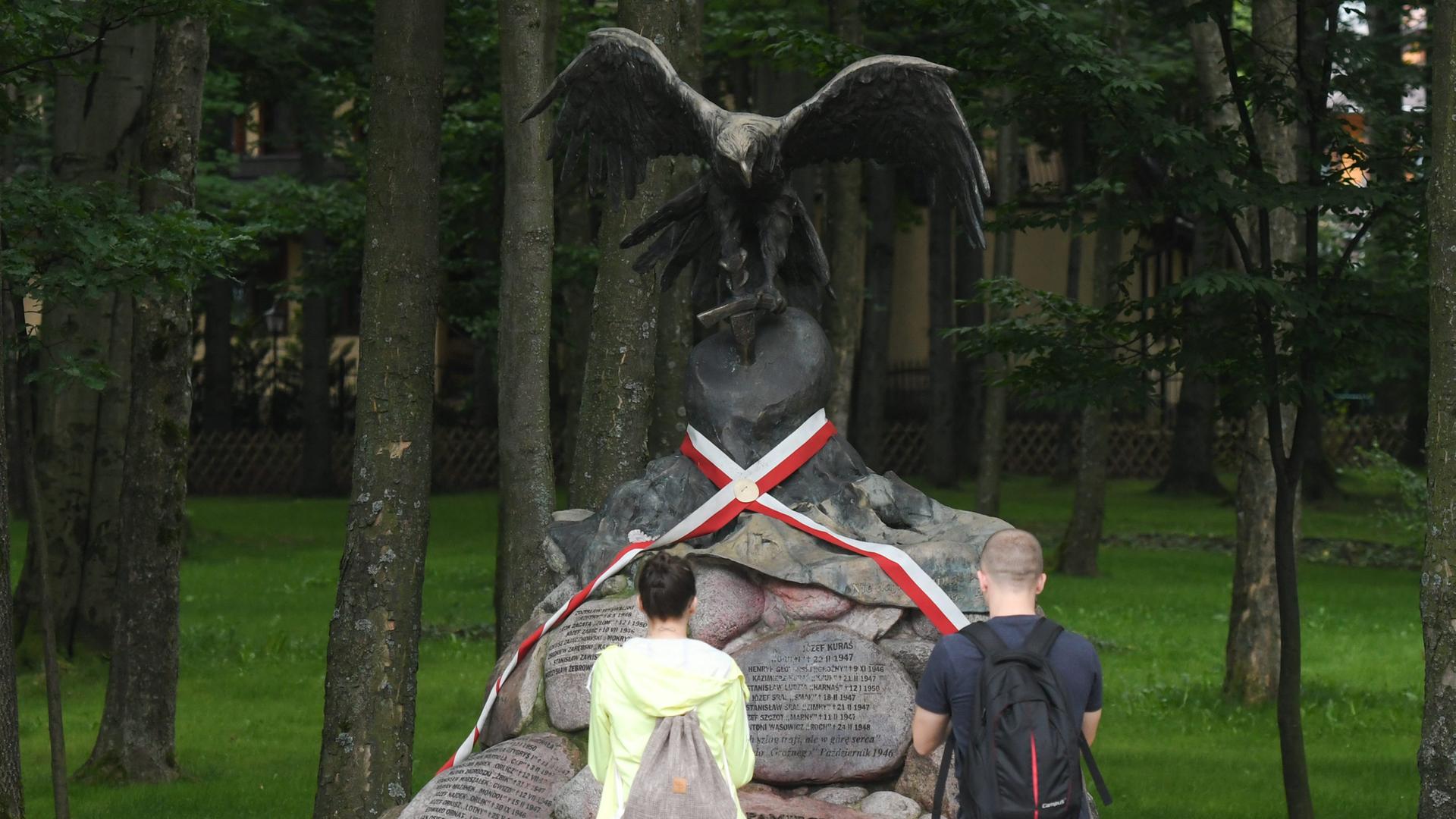 Junge Menschen stehen vor dem Denkmal zu ehren von Jozef Kuras.
