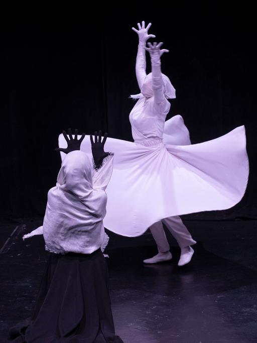 Weibliche Mitglieder der Teheraner Theatergruppe Khishtan führen ein Stück am Todestag des persischen Dichters Rumi auf. Der Hintergrund ist dunkel, die Kleidung hell.