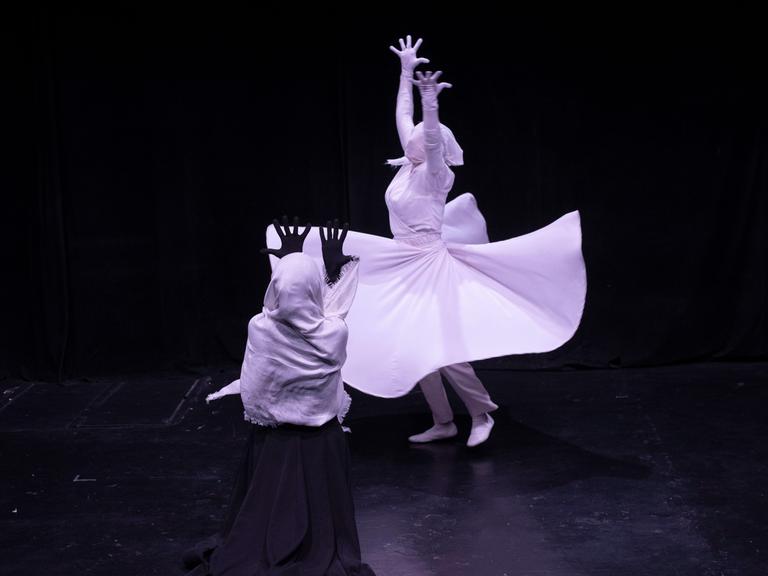 Weibliche Mitglieder der Teheraner Theatergruppe Khishtan führen ein Stück am Todestag des persischen Dichters Rumi auf. Der Hintergrund ist dunkel, die Kleidung hell.