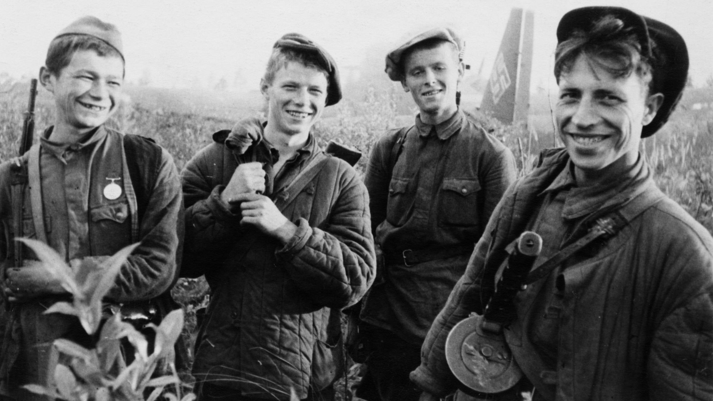 Vier junge Partisanen, die gerade ein deutsches Transportflugzeug in Brand gesetzt haben während des 2. Weltkriegs.