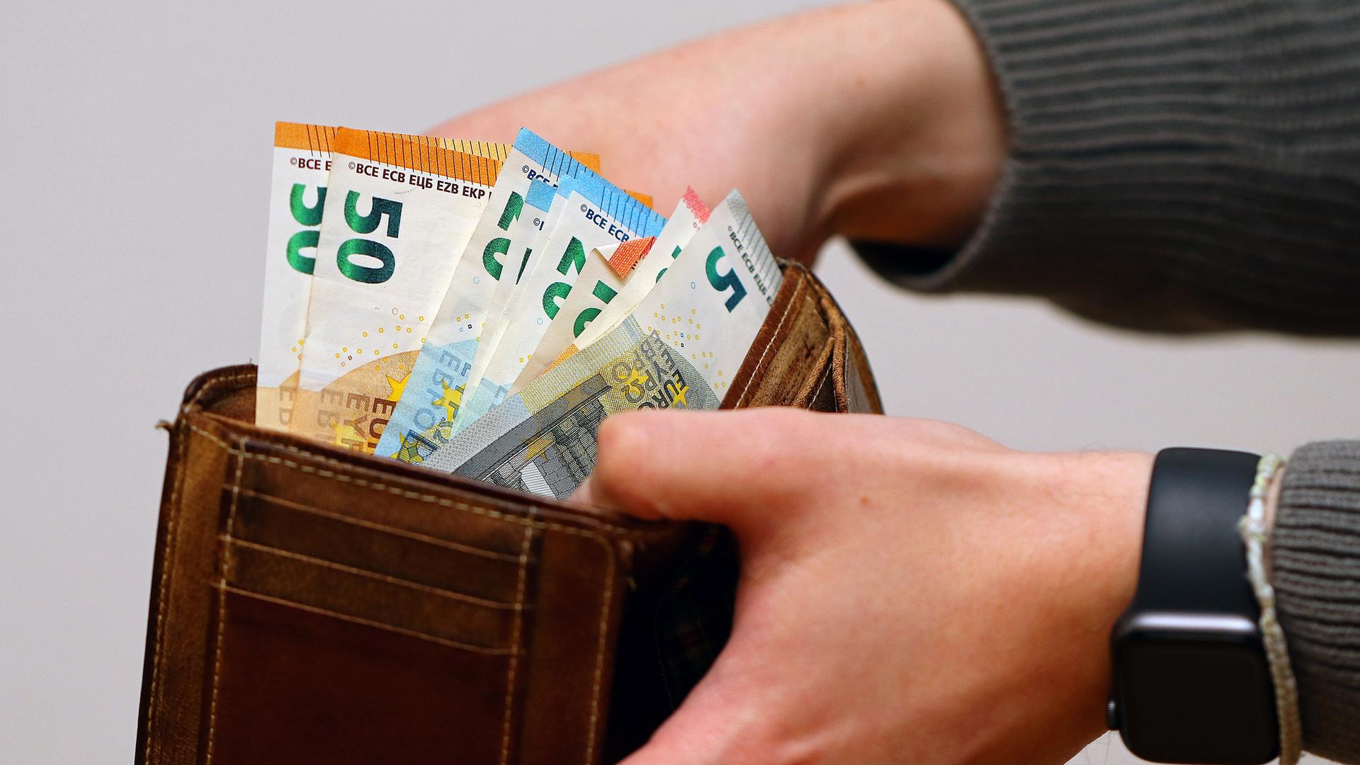 Eine Frau zählt ihre Geldscheine ihrem Portemonnaie.