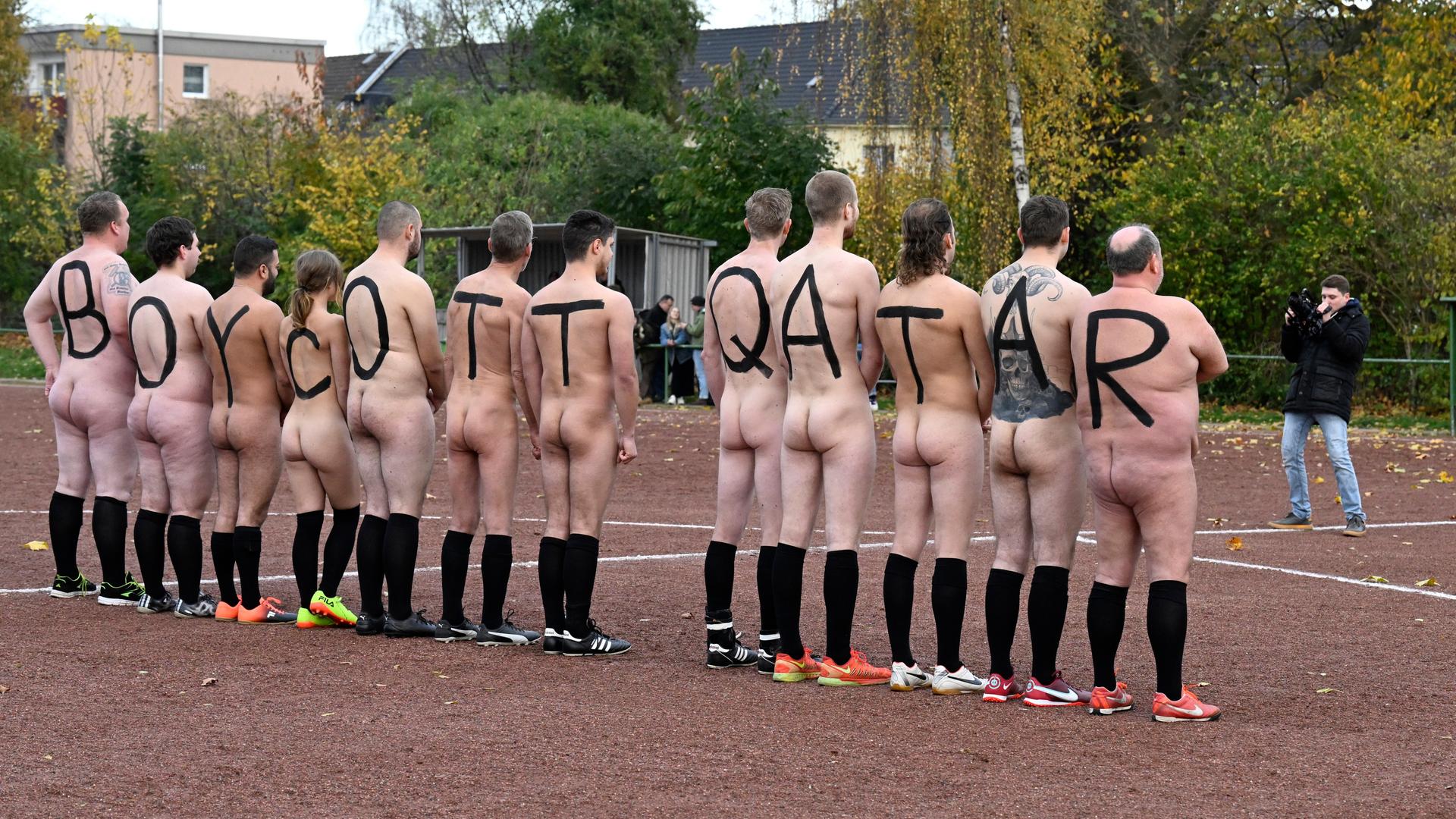 Spieler der deutschen NACKtionalmannschaft lassen sich nackt fotografieren. Die Spieler tragen auf dem Rücken große Buchstaben gemalt, die zusammen "BOYCOTT QATAR" ergeben.