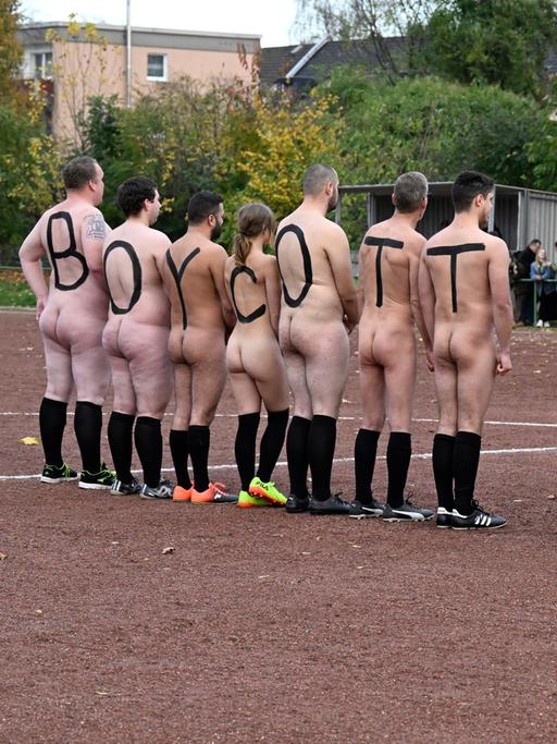 Spieler der deutschen NACKtionalmannschaft lassen sich nackt fotografieren. Die Spieler tragen auf dem Rücken große Buchstaben gemalt, die zusammen "BOYCOTT QATAR" ergeben.