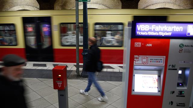 Fahrgäste laufen an einem Fahrkartenautomaten auf dem Bahnsteig der Ringbahn der Berliner S-Bahn vorbei.