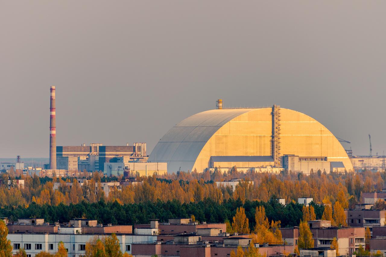 Luftaufnahme von der Spitze eines verlassenen Wohnhochhauses in Pripyat, Sperrzone von Tschernobyl, mit dem explodierten Reaktorblock 4, der von dem neuen Sarkophag bedeckt ist.