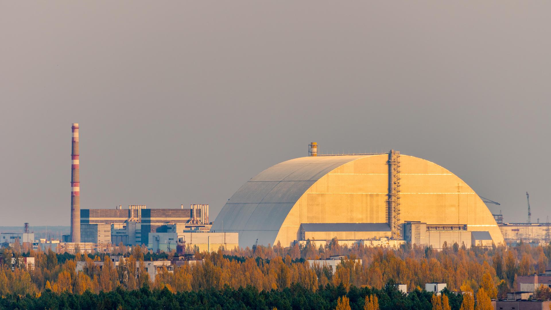 Luftaufnahme von der Spitze eines verlassenen Wohnhochhauses in Pripyat, Sperrzone von Tschernobyl, mit dem explodierten Reaktorblock 4, der von dem neuen Sarkophag bedeckt ist. Luftaufnahme von der Spitze eines verlassenen Wohnhochhauses in Pripyat, Sperrzone von Tschernobyl, mit dem explodierten Reaktorblock 4, der von dem neuen Sarkophag bedeckt ist.