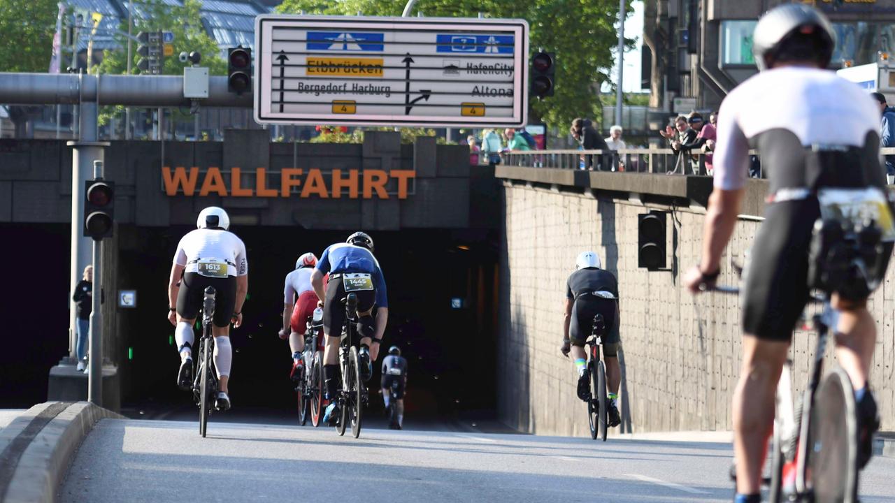 Teilnehmer des Ironman-Rennens in Hamburg fahren auf ihren Fahrrädern an der Kunsthalle in einen Tunnel.