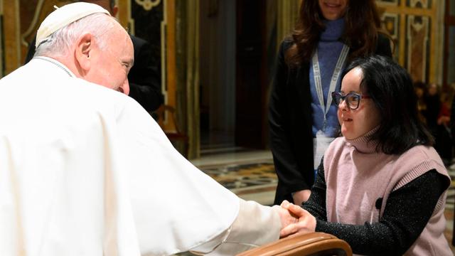Papst Franziskus gibt einer Betroffenen am Tag der Menschen mit Behinderung die Hand.