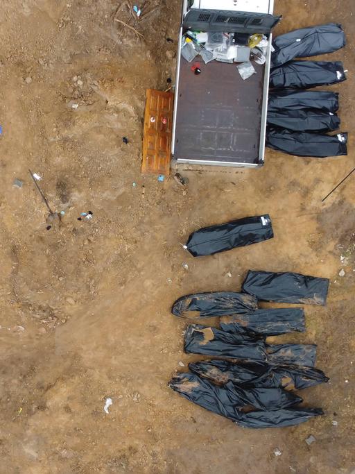 Schwarze Leichensäcke liegen neben einem Transporter im ukrainischen Ort Butscha, wo Leichen aus einem Massengrab geborgen wurden.