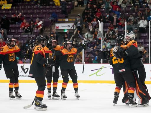 Mehrere Eishockey-Spielerinnen mit deutschem Trikot jubeln nach einem Tor.