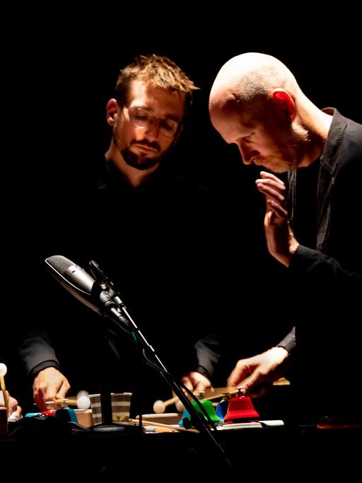 Die vier Musiker von Sō Percussion spielen im Scheinwerferlicht auf der Bühne eng zusammen an einem Instrument