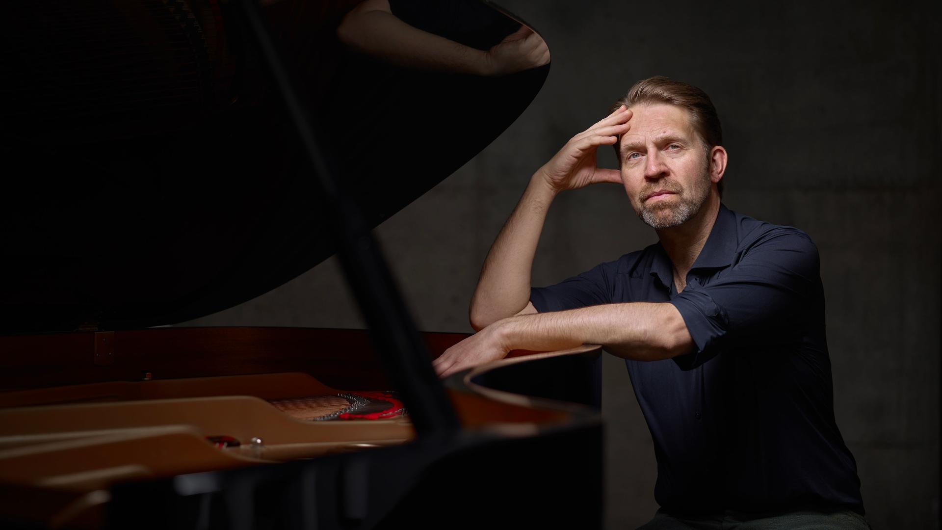 Leif Ove Andsnes sitzt am Ende eines aufgeklappten Flügels und stützt einen Arm auf das schwarze Holz. Leif Ove Andsnes sitzt am Ende eines aufgeklappten Flügels und stützt einen Arm auf das schwarze Holz.