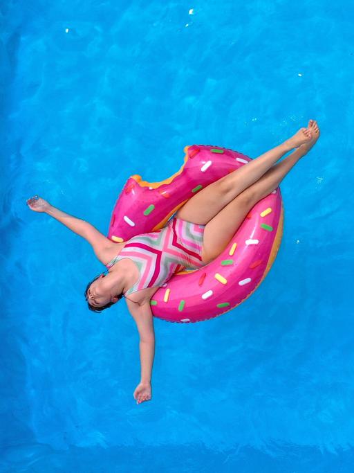 Eine Person schwimmt mit einem Schwimmring in einem Swimmingpool im Garten.