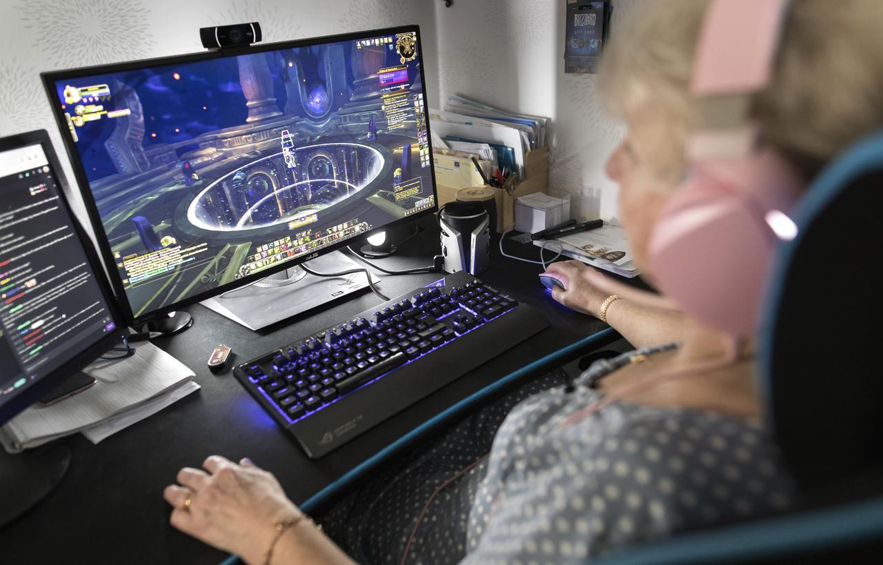 Eine Frau mittleren Alters sitzt am Schreibtisch und spielt auf ihrem Computer "World of Warcraft".
