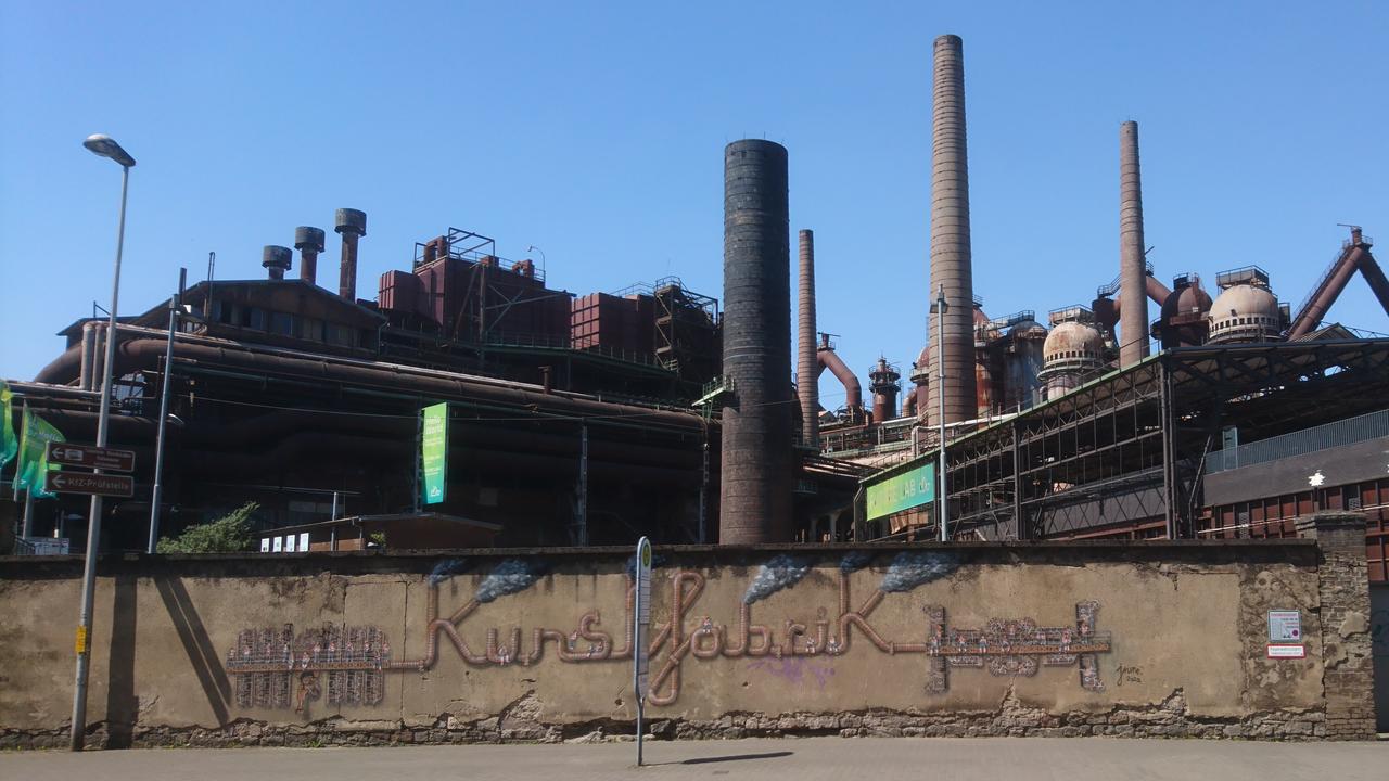 Graffiti mit dem Schriftzug "Kunstfabrik" an der Außenmauer der Völklinger Hütte Graffiti mit dem Schriftzug "Kunstfabrik" an der Außenmauer der Völklinger Hütte