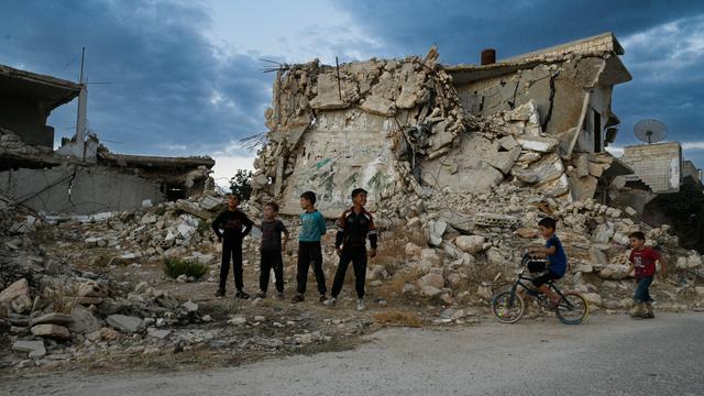 Ein paar Kinder stehen vor zerstörten Häuserruinen in der nordwestsyrischen Region Idlib