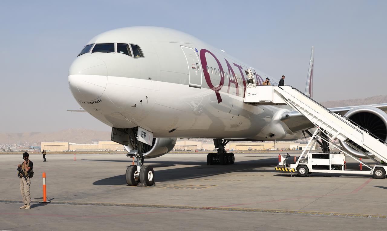 Ein Flugzeug steht am Flughafen von Kabul. Wachposten der Taliban mit Maschinengewehren sind um das Flugzeug herum postiert. Ein Flugzeug steht am Flughafen von Kabul. Wachposten der Taliban mit Maschinengewehren sind um das Flugzeug herum postiert.