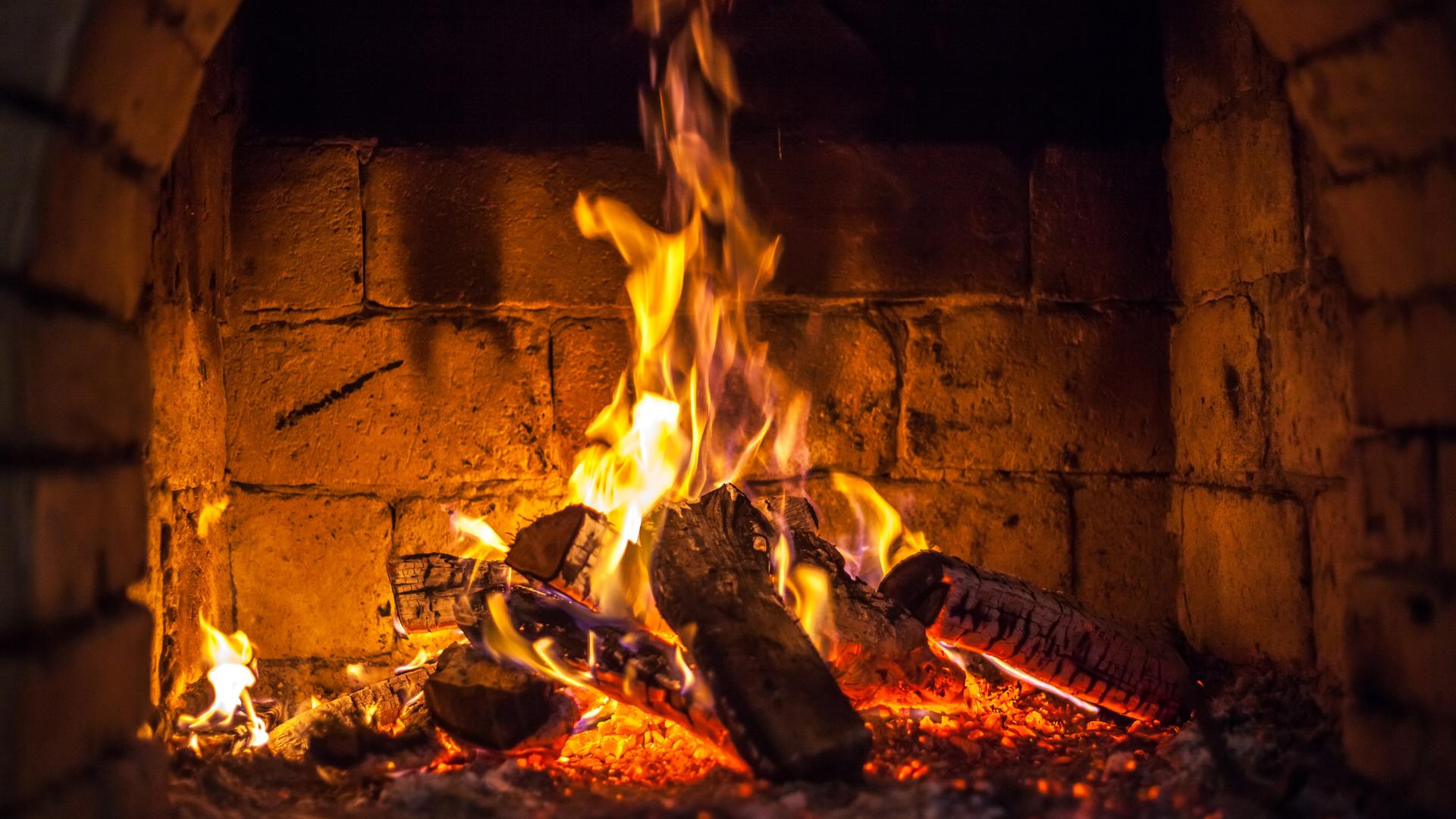 Ein Feuer brennt in einem Kamin. Er ist aus großen Steinen gebaut. Ein Feuer brennt in einem Kamin. Er ist aus großen Steinen gebaut.
