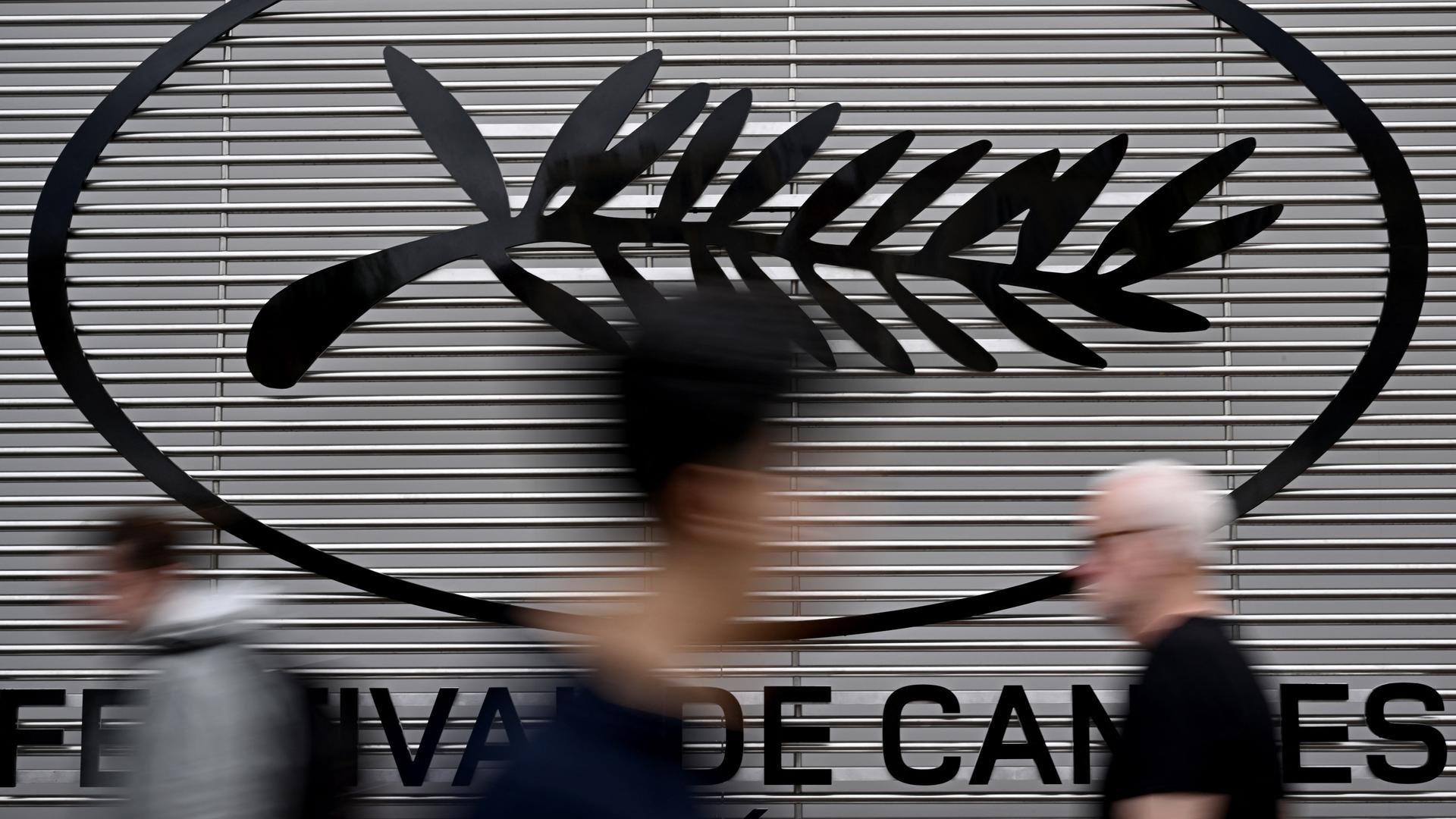 Fußgänger laufen am Logo des Filmfestivals von Cannes in Frankreich vorbei. Fußgänger laufen am Logo des Filmfestivals von Cannes in Frankreich vorbei.