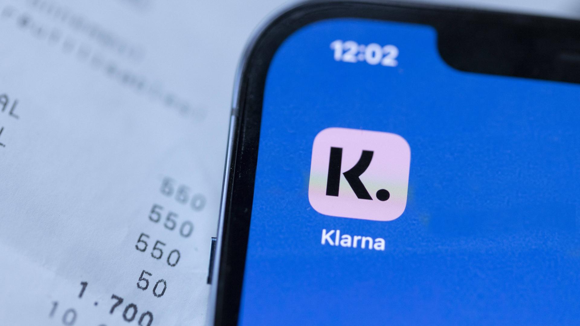 Ein Smartphone mit der Klarna-App vor ein paar Rechnungen Ein Smartphone mit der Klarna-App vor ein paar Rechnungen