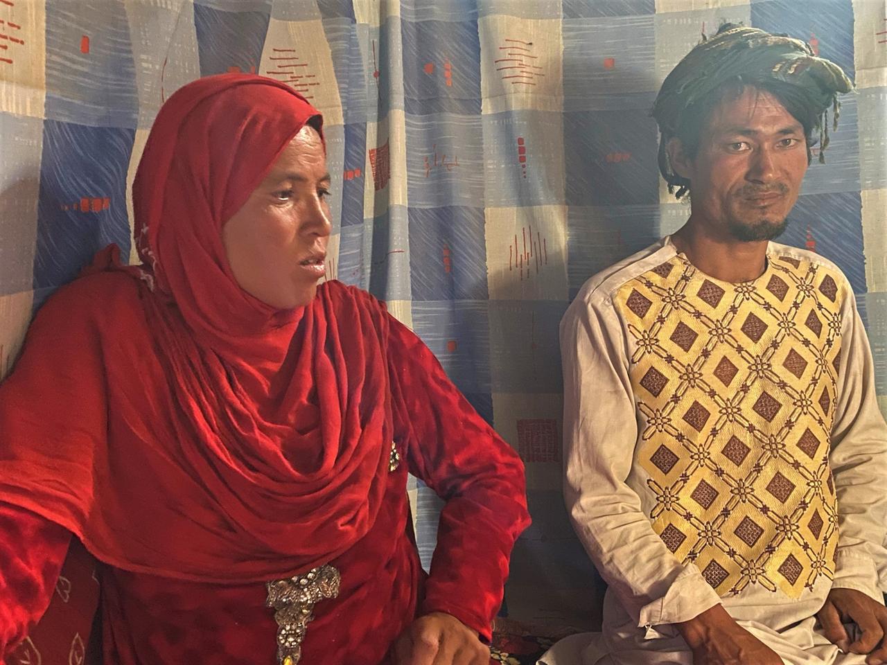 Ein Paar in afghanischer Tracht - sie mit einem roten Tuch über dem Kopf - sitzt nebeinander auf dem Boden. Ein Paar in afghanischer Tracht - sie mit einem roten Tuch über dem Kopf - sitzt nebeinander auf dem Boden.