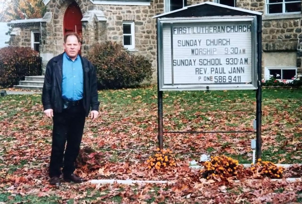 Michael Hanser steht als erwachsener Mann vor einer Kirche in Pennsylvania.