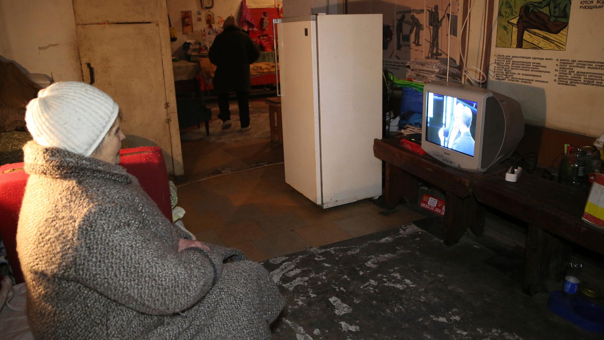 Eien Frau sitzt in einem Raum und schaut TV Eien Frau sitzt in einem Raum und schaut TV