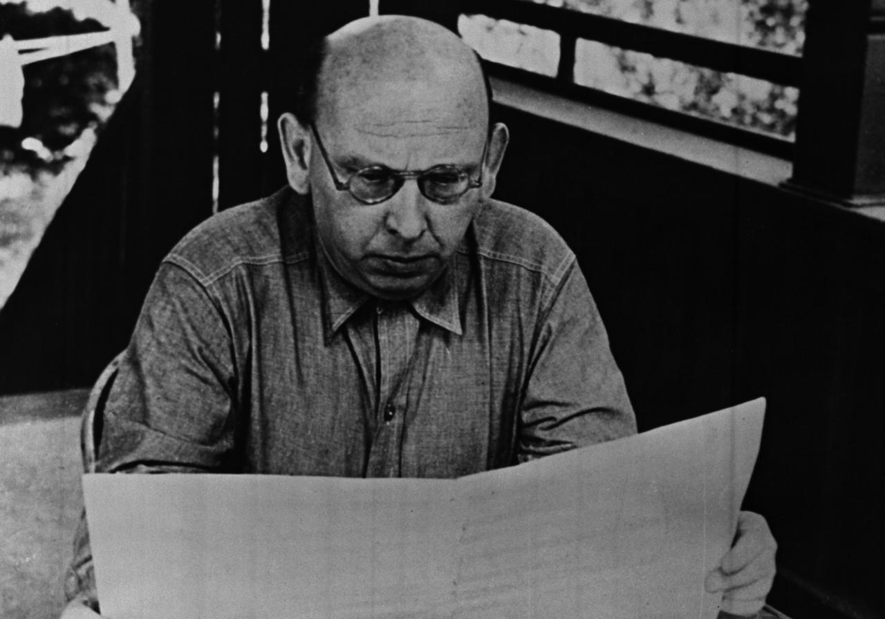 Hanns Eisler (1898-1962)  in Malibu (USA), Foto von 1946. Zu sehen: Der Komponist Hanns Eisler sitzt an einem Tisch und liest eine Partitur. 

