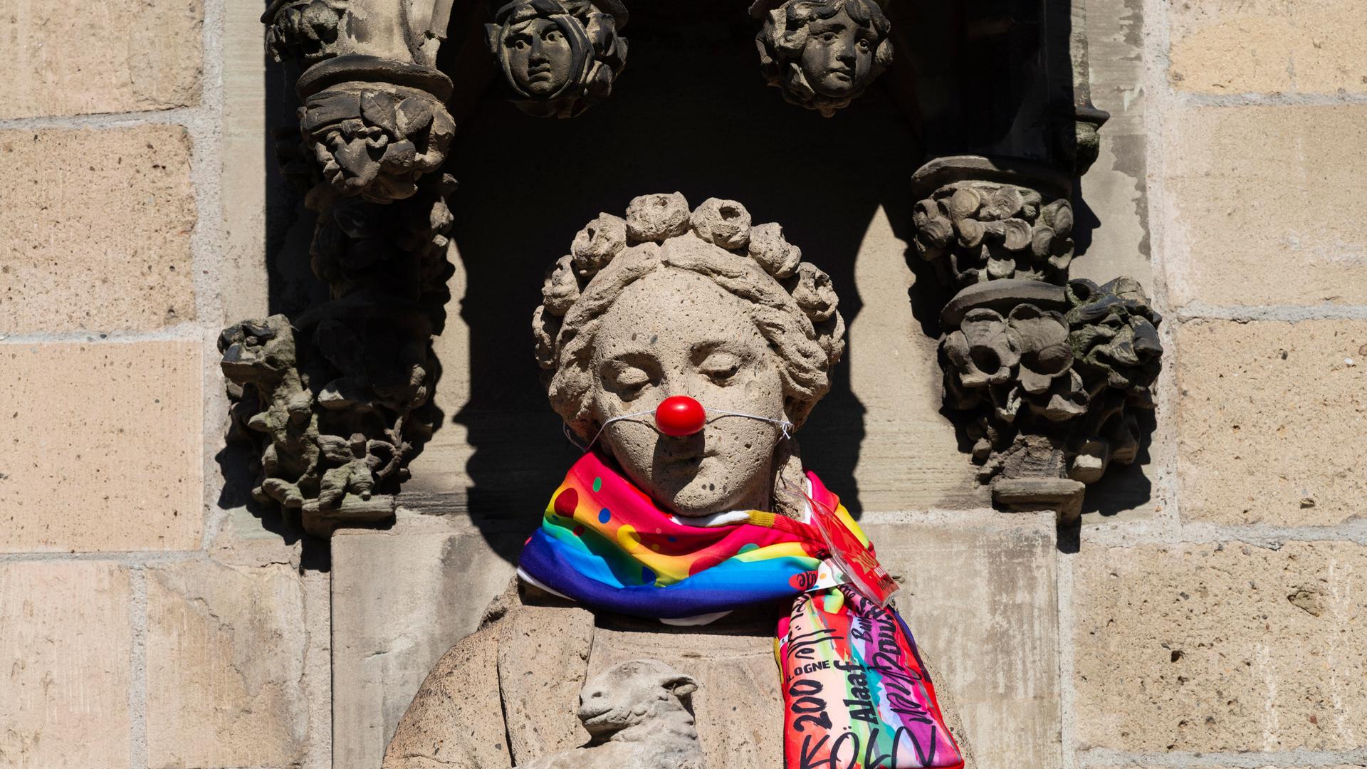 Mit Karnevalsschal und roter Pappnase drapierte ist die Heilige Agnes an der Agneskirche in Köln. Mit Karnevalsschal und roter Pappnase drapierte ist die Heilige Agnes an der Agneskirche in Köln.