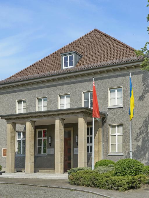 Blick auf das Deutsch-Russische Museum in Berlin-Karlshorst, vor dem die deutsche, die russische, die ukrainische und die belarussiche Flagge zu sehen sind.