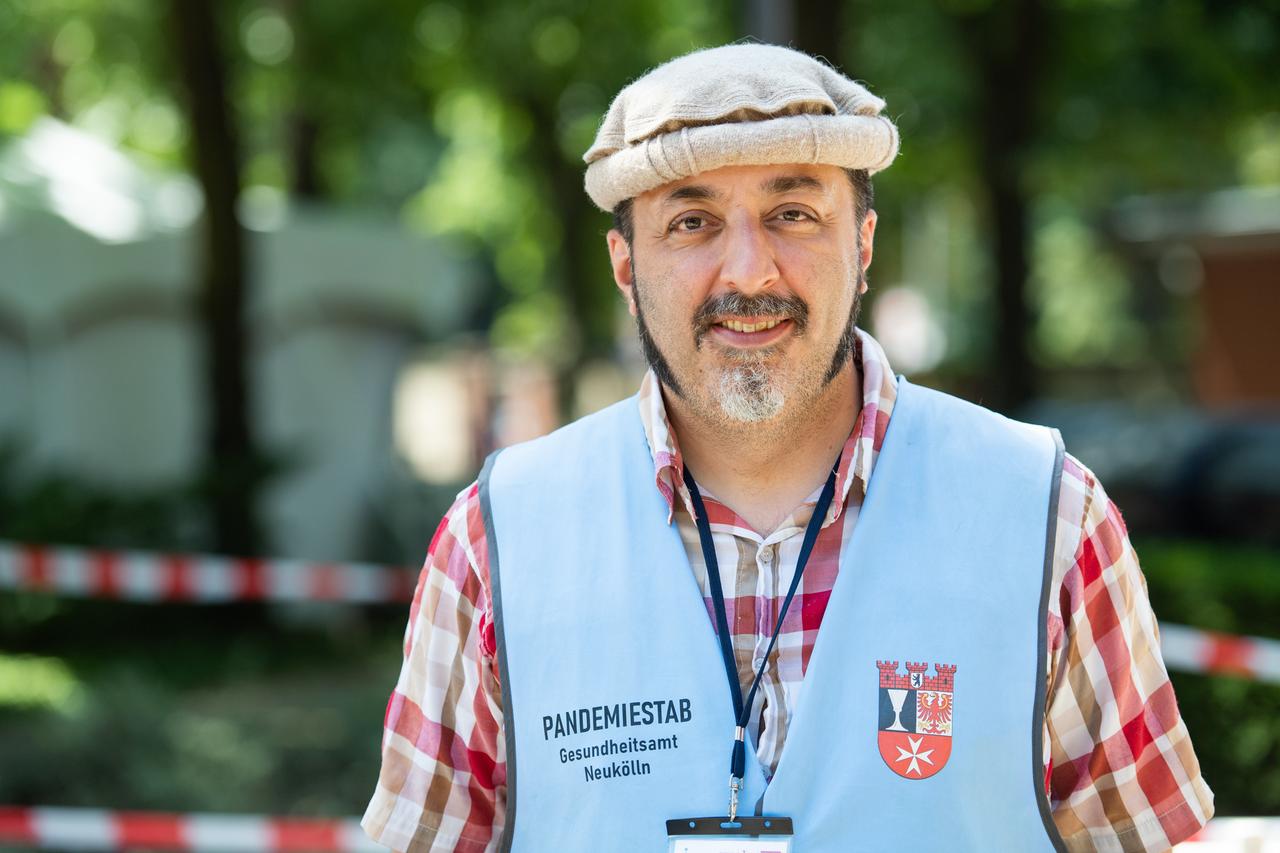 Porträt von Taman Noor in einer hellblauen Weste des Bezirksamtes Berlin-Neukölln Porträt von Taman Noor in einer hellblauen Weste des Bezirksamtes Berlin-Neukölln
