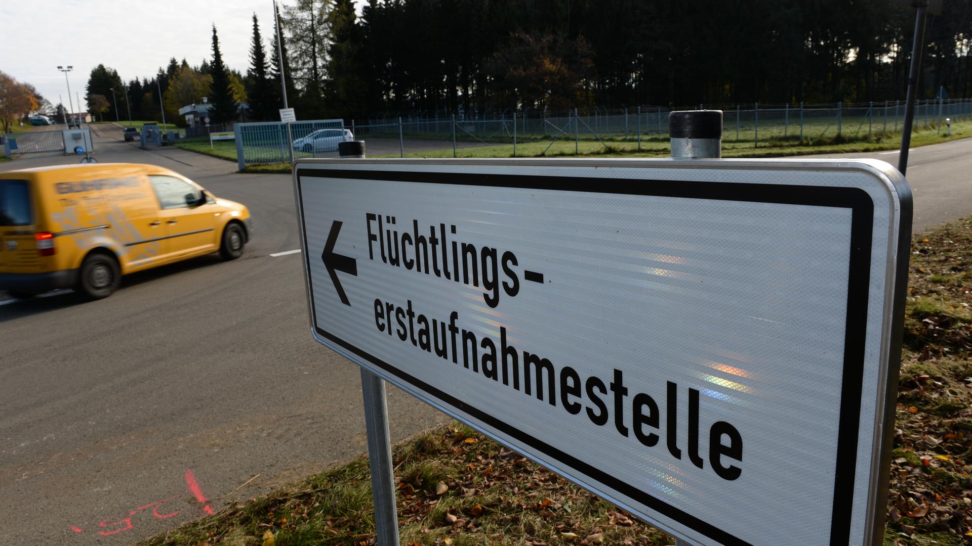 Ein Verkehrszeichen weist den Weg zur Flüchtlingserstaufnahmestelle. Auf dem weißen, rechteckigen Schild steht ein Pfeil und das Wort Flüchtlingserstaufnahmestelle Ein Verkehrszeichen weist den Weg zur Flüchtlingserstaufnahmestelle. Auf dem weißen, rechteckigen Schild steht ein Pfeil und das Wort Flüchtlingserstaufnahmestelle