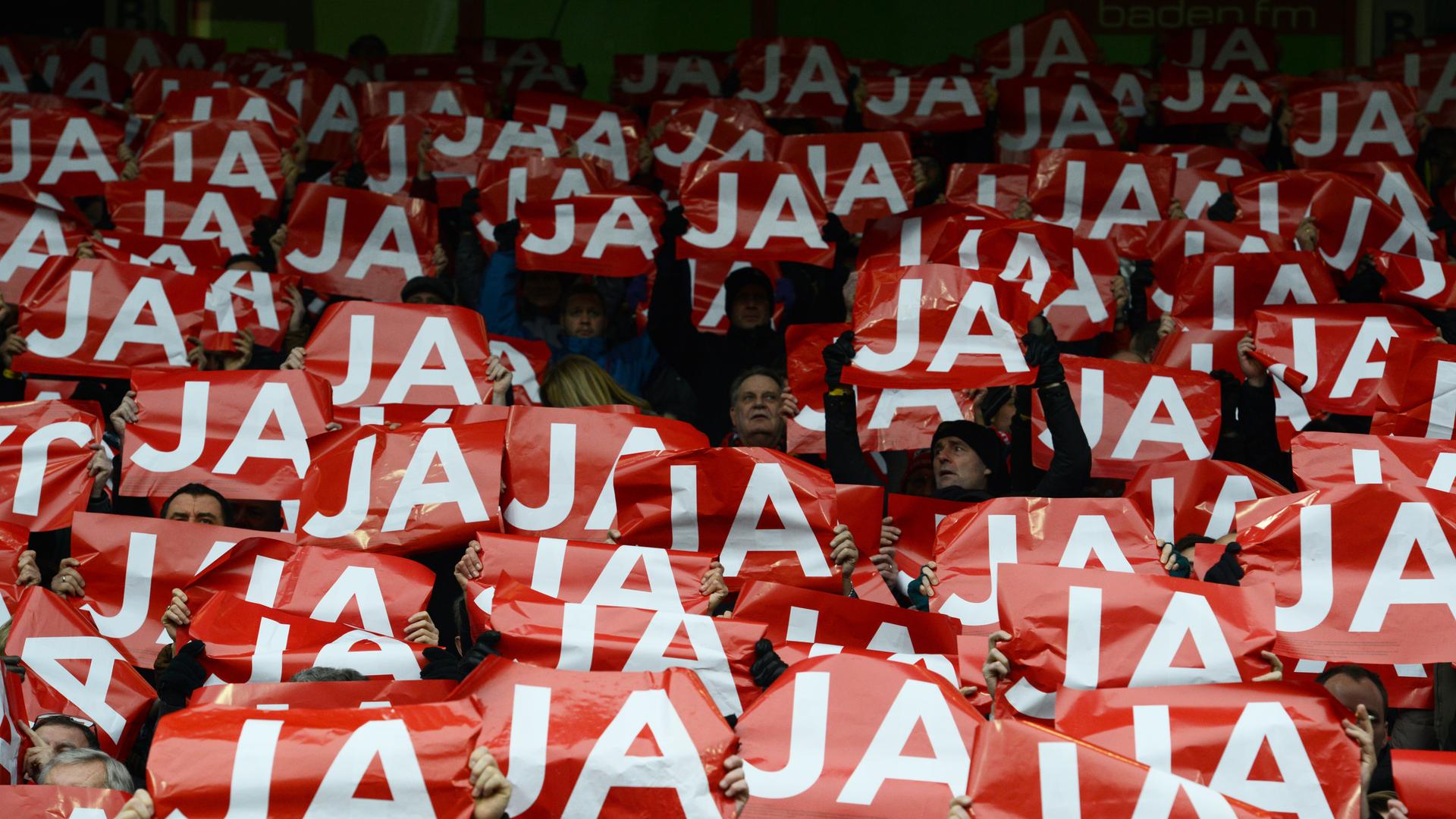 Fans des SC Freiburg halten auf der Tribüne im alten Stadion rote Schilder mit der Aufschrift "JA" in weißen Buchstaben hoch. Es sind rund 50 Schilder zu sehen und kaum Gesichter, da diese hinter dem Schilderwald nicht zu sehen sind. Fans des SC Freiburg halten auf der Tribüne im alten Stadion rote Schilder mit der Aufschrift "JA" in weißen Buchstaben hoch. Es sind rund 50 Schilder zu sehen und kaum Gesichter, da diese hinter dem Schilderwald nicht zu sehen sind.