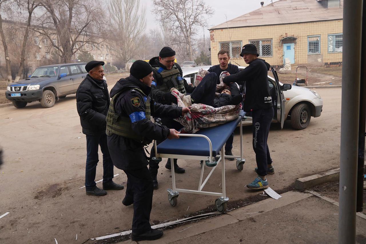 Ukrainische Helfer versorgen einen Mann, der bei einem Angriff auf ein Krankenhaus in Mariupol verletzt wurde. Er liegt auf einer Liege. Ukrainische Helfer versorgen einen Mann, der bei einem Angriff auf ein Krankenhaus in Mariupol verletzt wurde. Er liegt auf einer Liege.