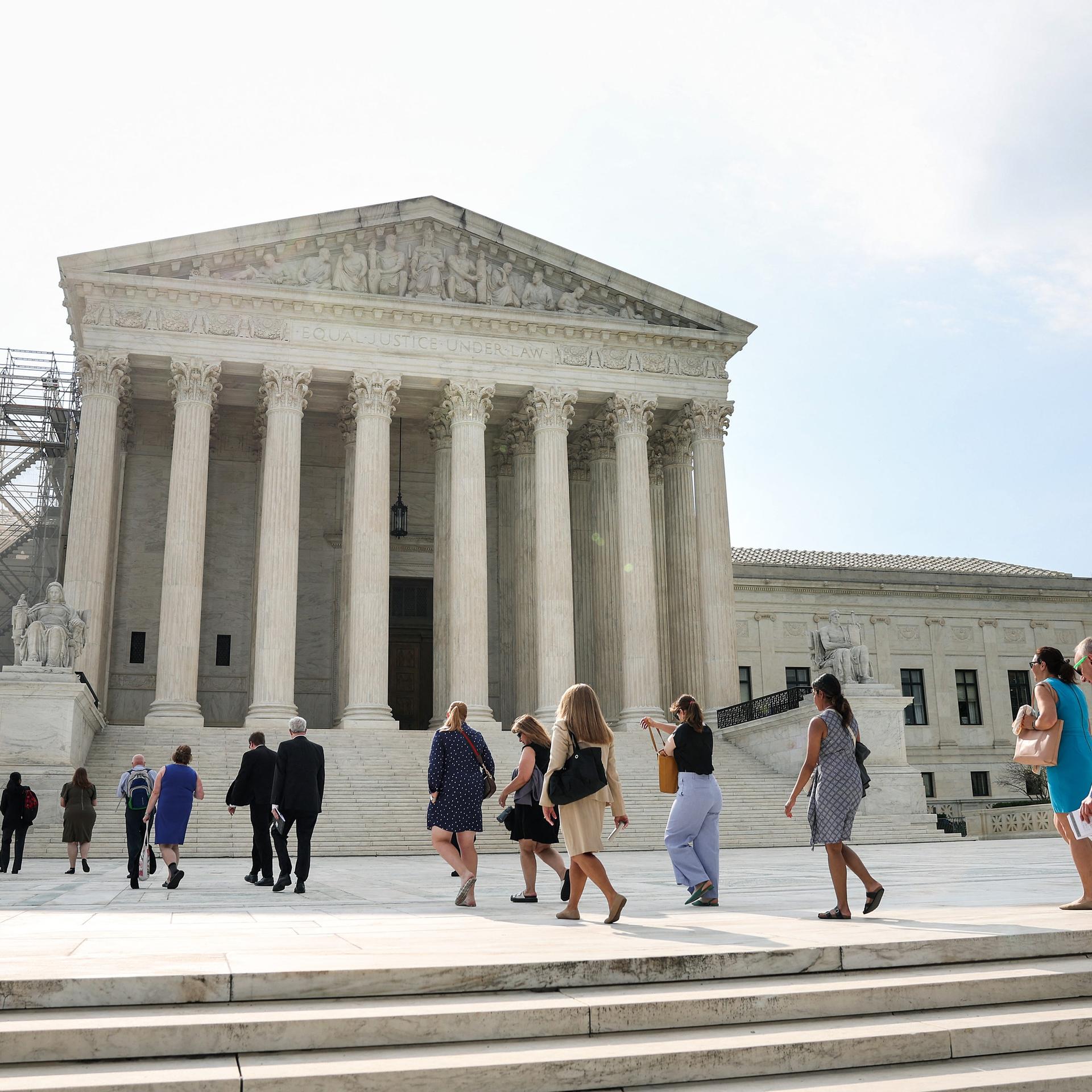 Die Menschen gehen eine Treppe hinauf und in das weiße Gerichtsgebäude des Obersten Gerichtshofs der USA