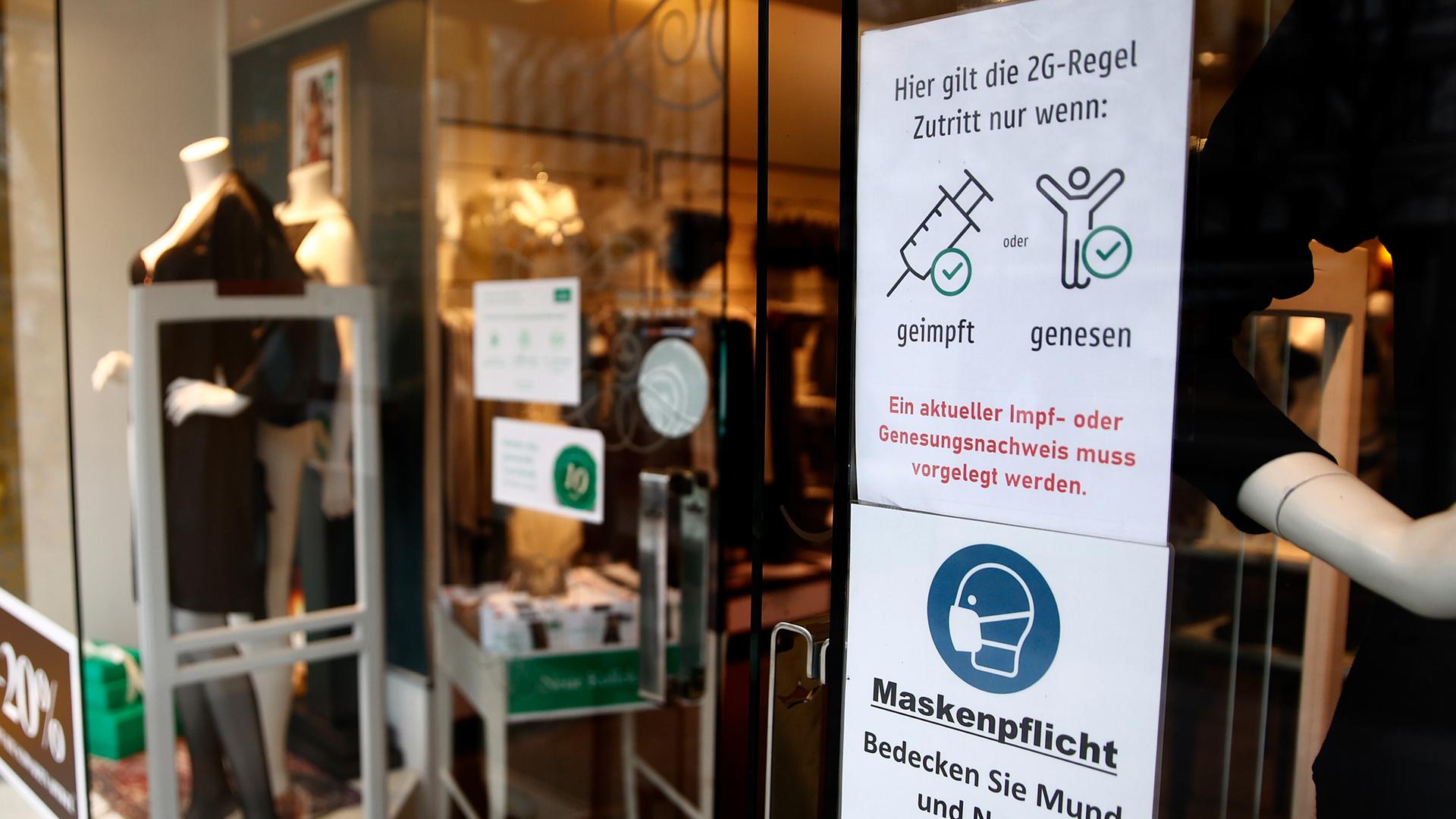 Ein Schild am Eingang eines Geschäftes weist auf die 2G-Regel und die Maskenpflicht hin. Ein Schild am Eingang eines Geschäftes weist auf die 2G-Regel und die Maskenpflicht hin.
