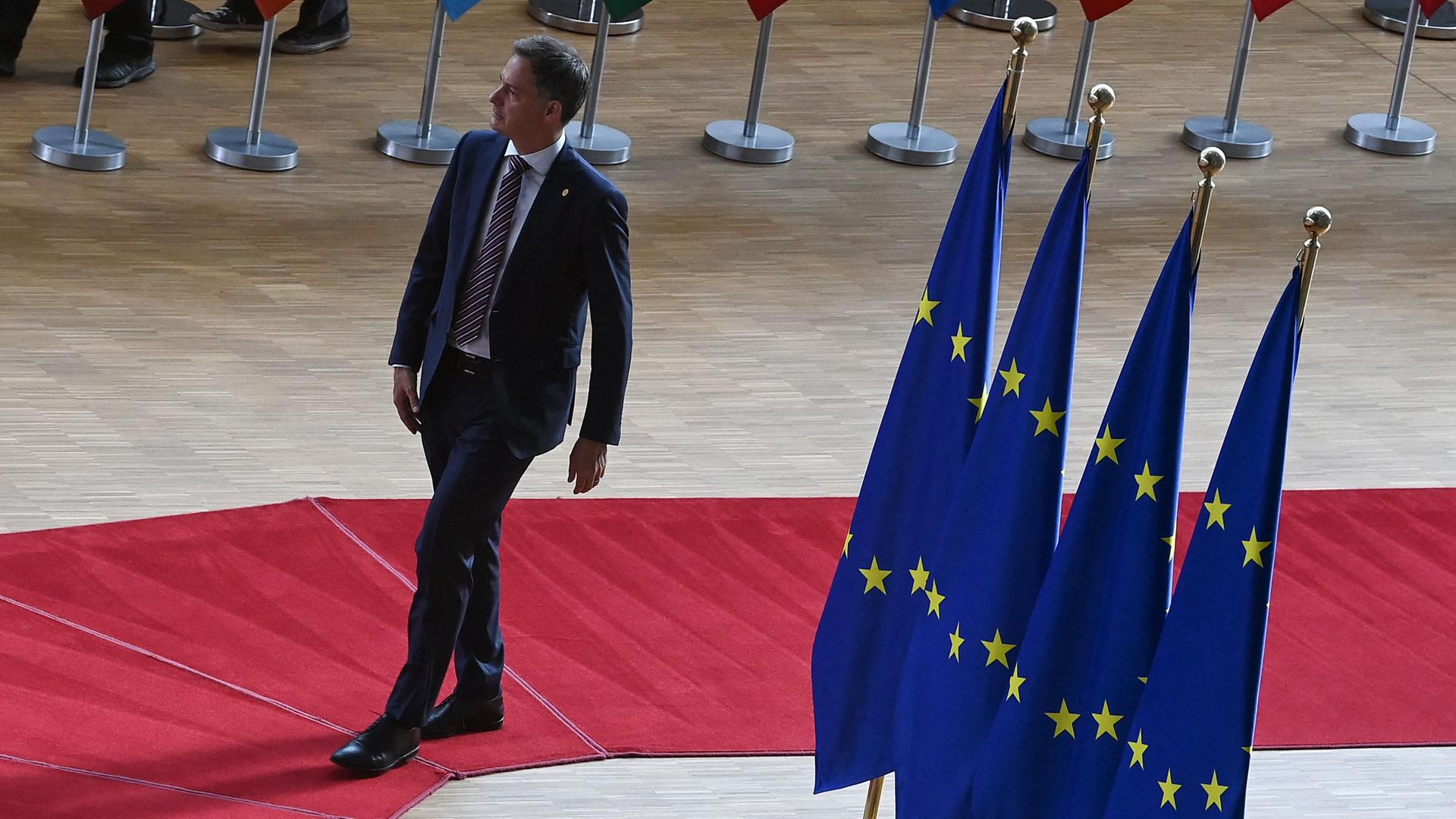 Der belgische Premierminister de Croo geht auf einem roten Teppich. Auf der rechten Seite mehrere EU-Fahnen. Im Hintergrund zum Teil zu sehen die EU-Fahnen der Mitgliedsländer. Der belgische Premierminister de Croo geht auf einem roten Teppich. Auf der rechten Seite mehrere EU-Fahnen. Im Hintergrund zum Teil zu sehen die EU-Fahnen der Mitgliedsländer.