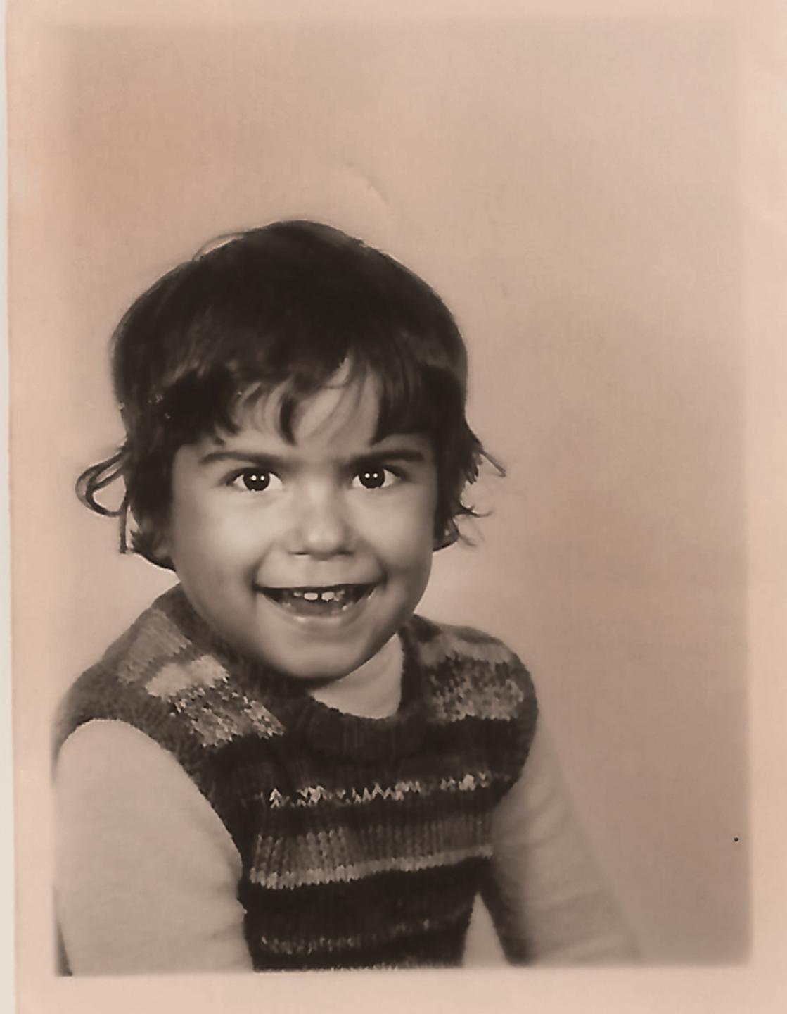 Schwarz-weiss Foto eines Kindes mit gestreiftem Pullunder und dunklen Haaren.
