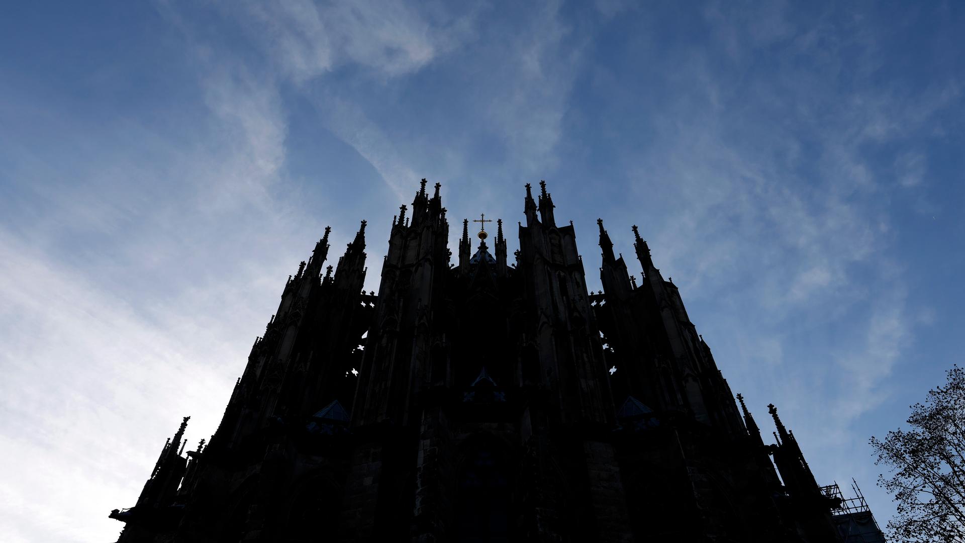 Der Kölner Dom ragt dunkel in einen blauen Himmel hinein. Der Kölner Dom ragt dunkel in einen blauen Himmel hinein.