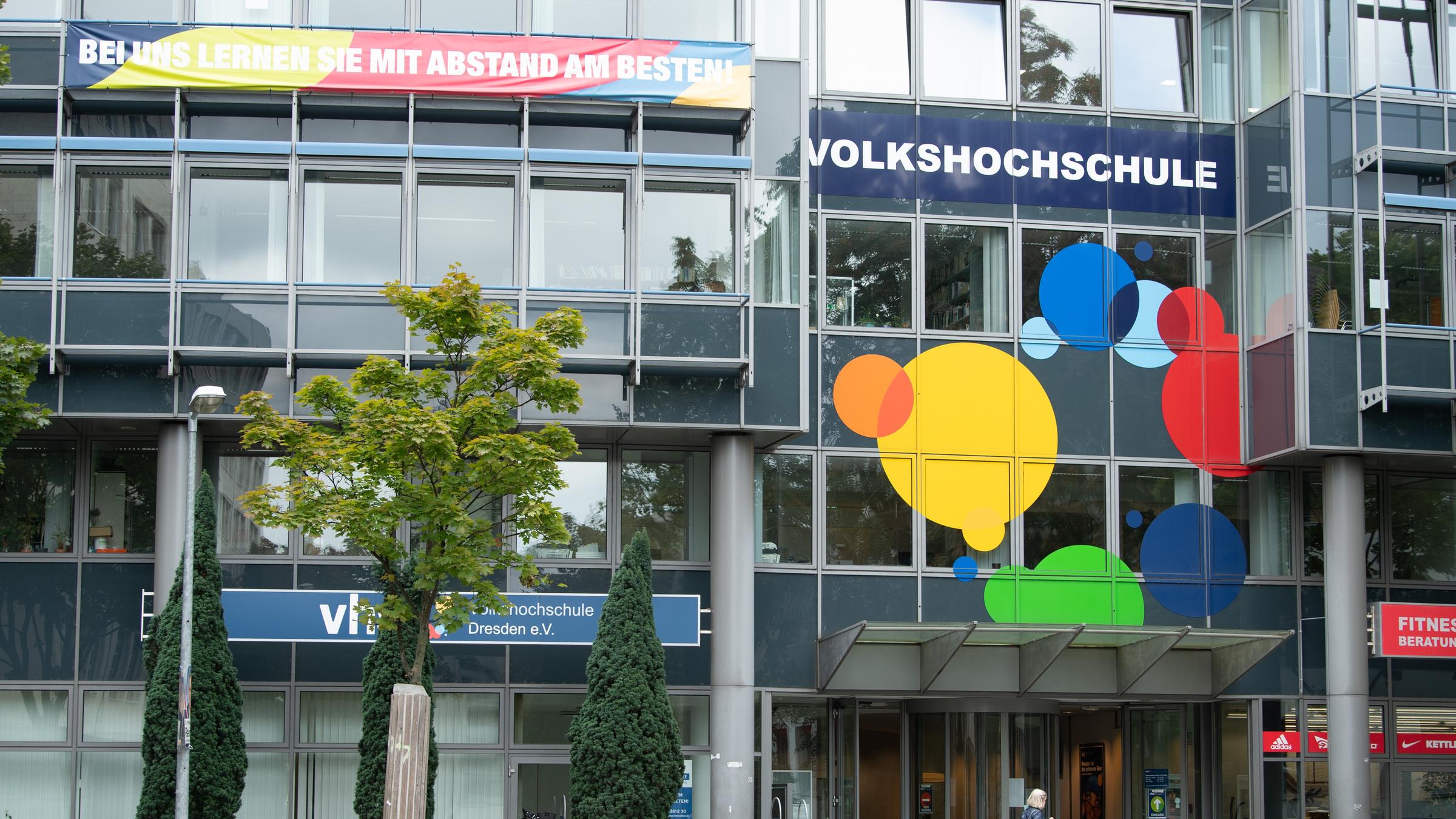 Eine Passantin geht vor dem Gebäude der Volkshochschule Dresden \(VHS\) entlang