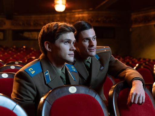 Zwei junge Soldaten in Uniformen der Roten Armee sitzen allein in einem Kinosaal.