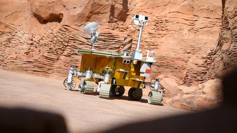 Das Bild zeigt ein Replikat des chinesischen Mars-Rovers "Zhurong" vor einer Felswand.